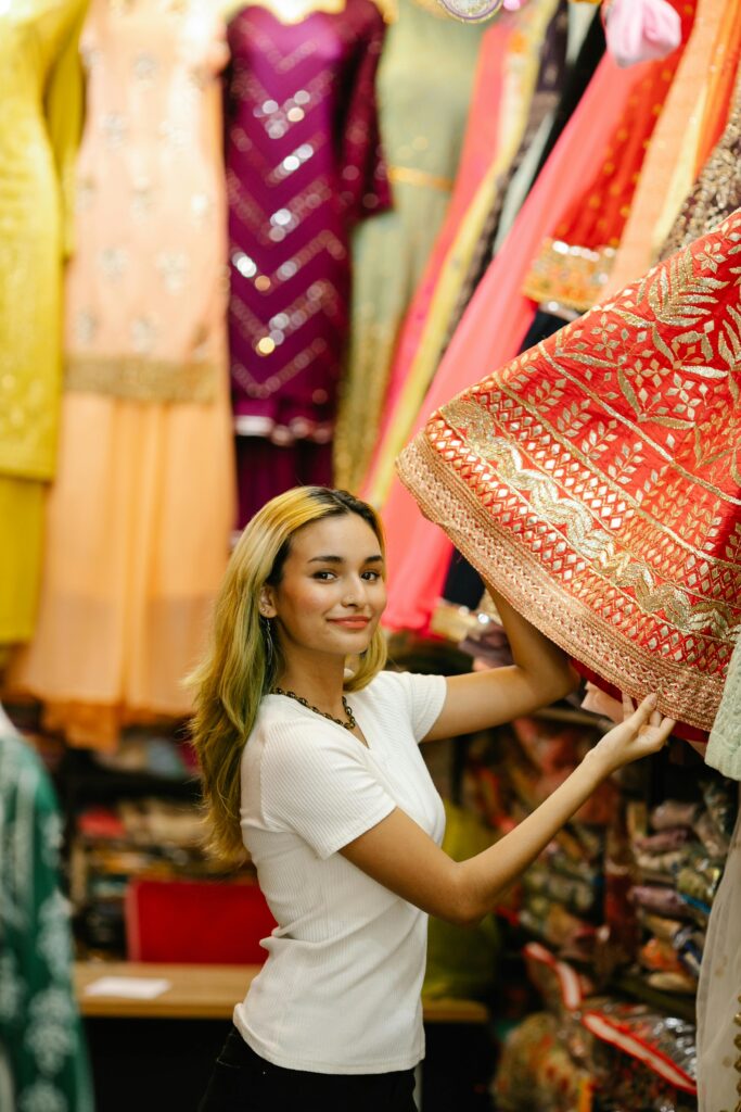A woman browsing colorful traditional Indian dresses in a clothing store.